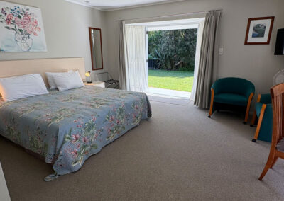 Deluxe King Studio at Ash Grove Motel in Paihia, featuring a spacious king bed and sliding doors opening to the garden.