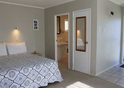 Interior of the King Studio Cottage at Ash Grove Motel, featuring a comfortable bed and private bathroom.