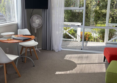 Lounge and dining area in the King Studio Cottage at Ash Grove Motel, with large windows overlooking the garden.