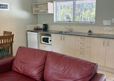 Fully equipped kitchen area in the One Bedroom Unit at Ash Grove Motel, showing dining table, bench space, and appliances.