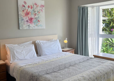 Bright bedroom in the One Bedroom Unit at Ash Grove Motel, featuring a comfortable queen bed and garden views.