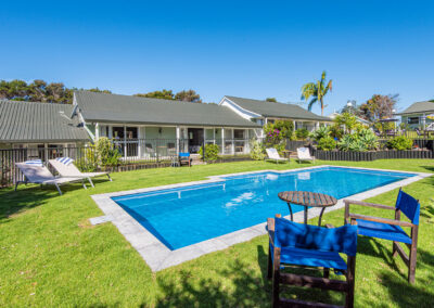 Outdoor swimming pool at Ash Grove Motel in Paihia, with sun loungers, garden seating, and studio units overlooking the pool.