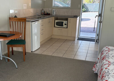 Kitchenette and dining area inside a Queen Studio Unit at Ash Grove Motel, with outdoor access and modern amenities.