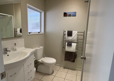 Bathroom in a Queen Studio Unit at Ash Grove Motel, featuring a modern vanity, toilet, heated towel rack, and tiled flooring.