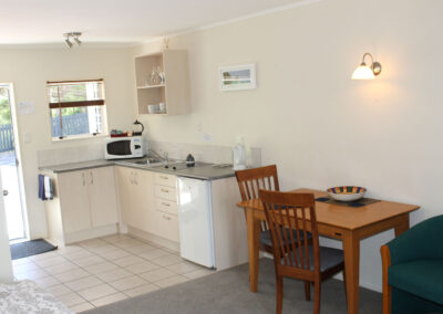 Kitchenette and dining area inside a Queen Studio Unit at Ash Grove Motel, featuring modern appliances and seating.