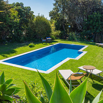Outdoor swimming pool at Ash Grove Motel in Paihia, surrounded by gardens, sun loungers, and a peaceful lawn setting